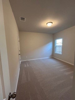 spare room with baseboards, visible vents, and dark colored carpet