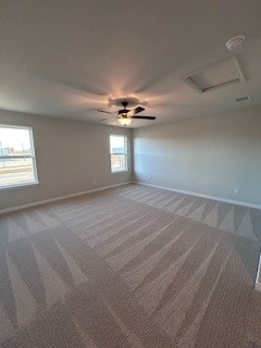 unfurnished room with carpet, attic access, and baseboards