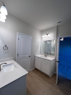 full bath with wood finished floors, two vanities, and a sink