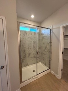 full bathroom with a stall shower, a closet, baseboards, and wood finished floors