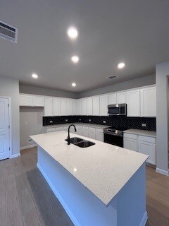 kitchen featuring tasteful backsplash, visible vents, electric stove, stainless steel microwave, and a sink