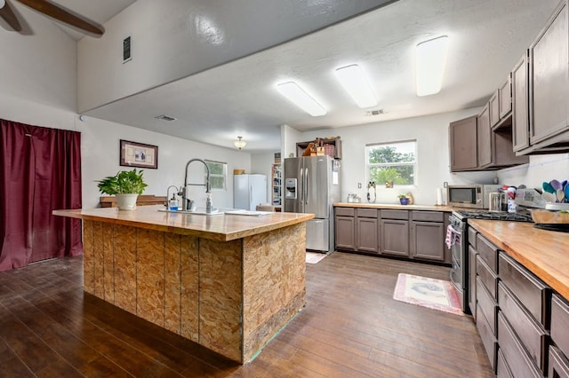 kitchen featuring dark wood finished floors, a center island with sink, visible vents, appliances with stainless steel finishes, and a sink