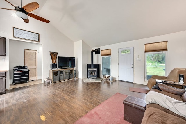 living area featuring ceiling fan, high vaulted ceiling, wood finished floors, and a wood stove