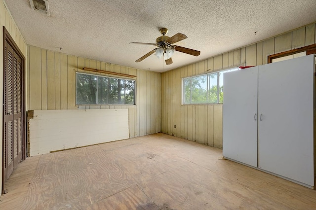 spare room with ceiling fan, visible vents, and a textured ceiling