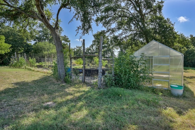 view of yard with fence, a greenhouse, and an outbuilding