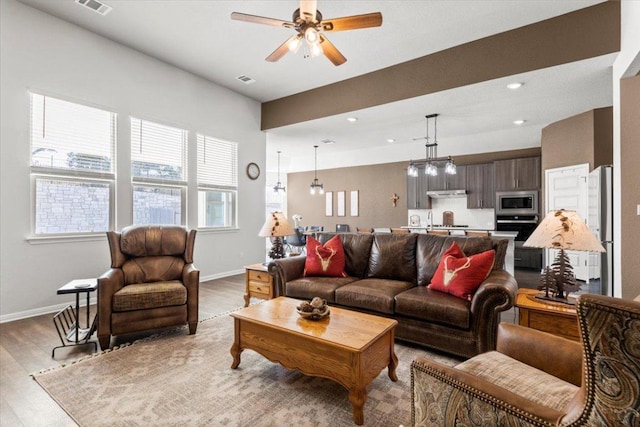 living area with baseboards, ceiling fan, recessed lighting, and light wood-style floors