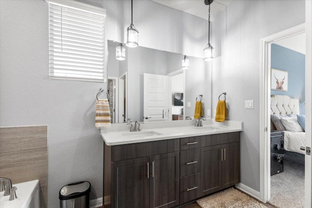 ensuite bathroom with ensuite bathroom, double vanity, a sink, and a tub