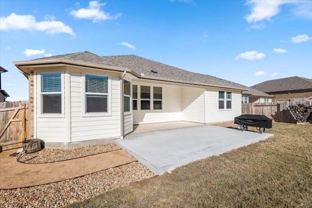 rear view of property with a shingled roof, a patio area, a lawn, and a fenced backyard