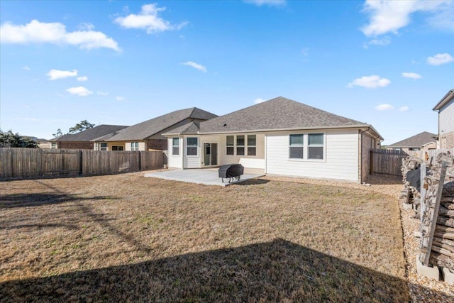 rear view of house with a patio, a shingled roof, a lawn, and a fenced backyard