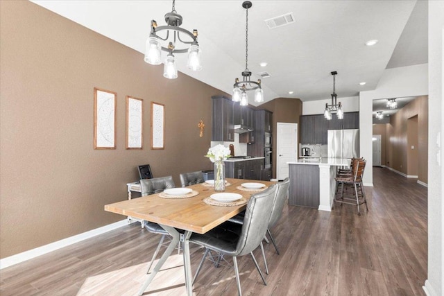 dining space featuring lofted ceiling, visible vents, an inviting chandelier, wood finished floors, and baseboards