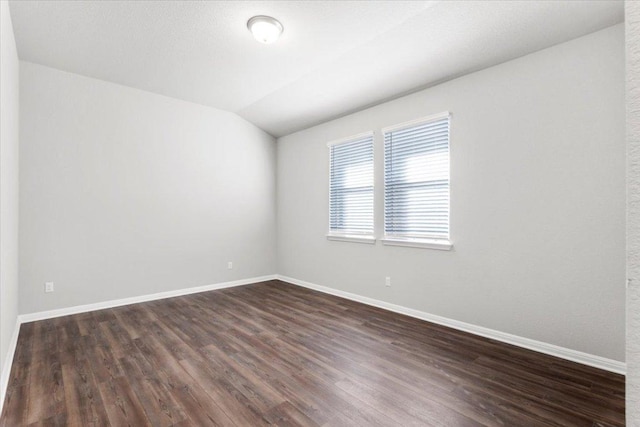 empty room with lofted ceiling, baseboards, and dark wood-style flooring