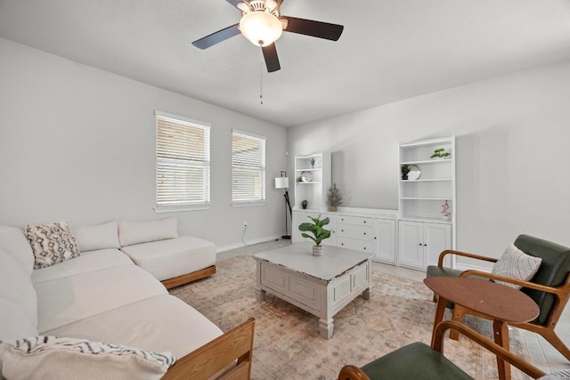 living area with ceiling fan and baseboards