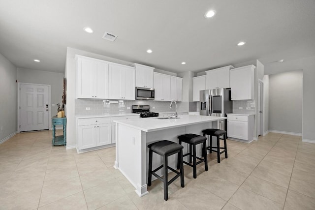 kitchen featuring a kitchen island with sink, stainless steel appliances, a sink, visible vents, and light countertops