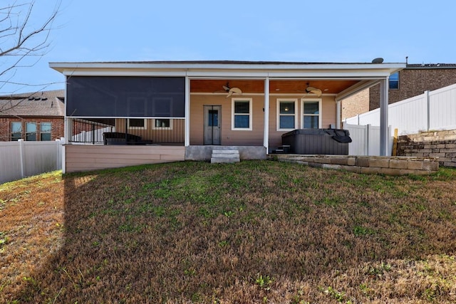 back of house featuring a sunroom, ceiling fan, fence, and a lawn