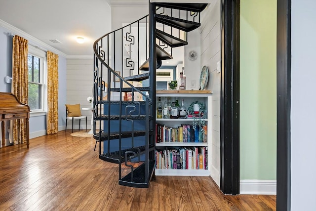 staircase featuring visible vents, crown molding, baseboards, and wood finished floors