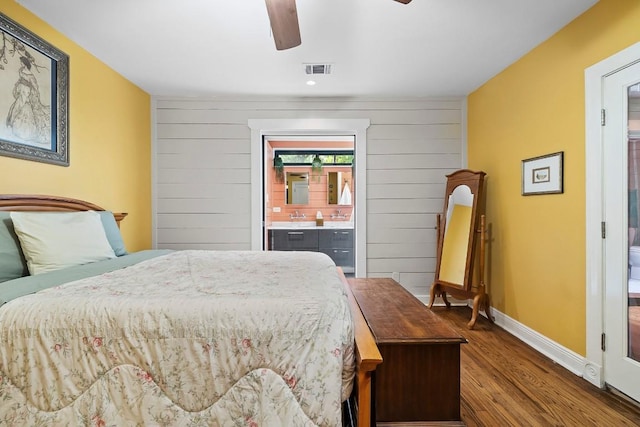 bedroom with baseboards, visible vents, ceiling fan, wood finished floors, and ensuite bathroom