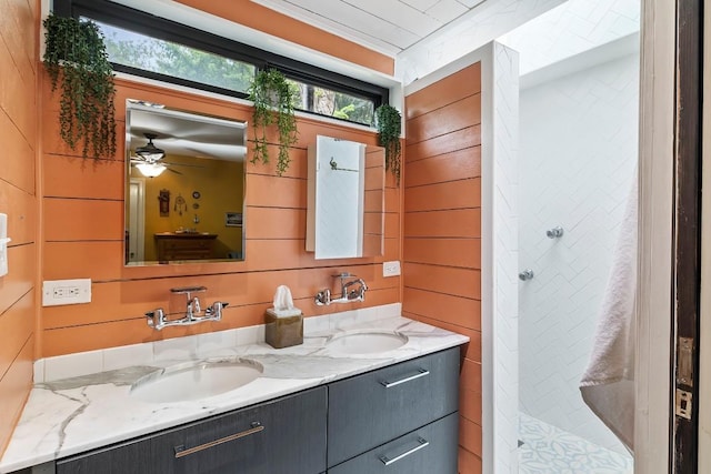 bathroom featuring double vanity, wooden walls, a sink, and tiled shower