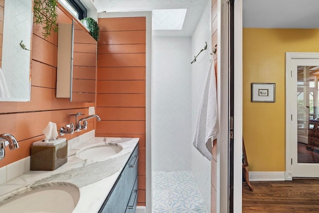 bathroom featuring wood finished floors, a sink, baseboards, and double vanity