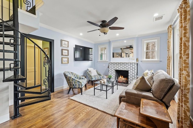 sitting room with a fireplace, wood finished floors, visible vents, stairway, and crown molding