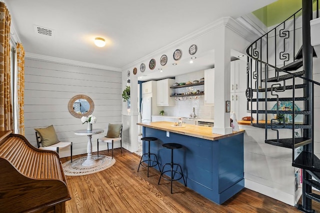 bar featuring dark wood-style flooring, visible vents, ornamental molding, a sink, and stairs