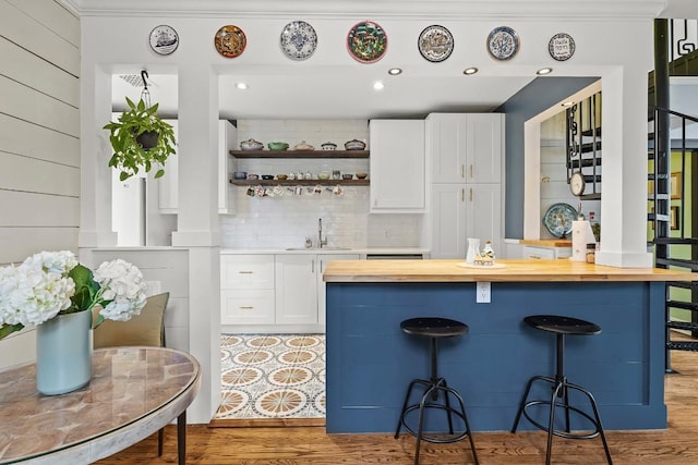 kitchen featuring white cabinets, a breakfast bar area, wooden counters, and a sink