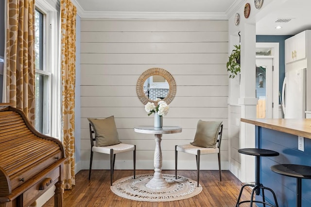 sitting room featuring visible vents, crown molding, baseboards, and wood finished floors