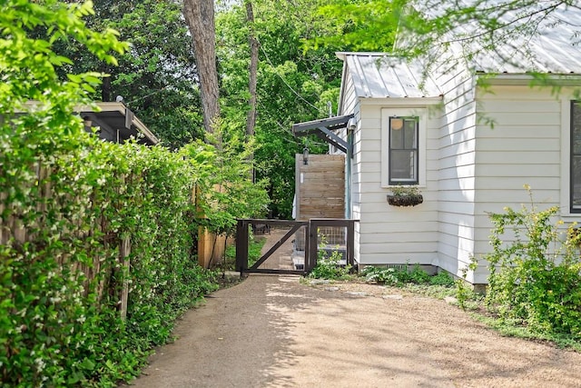 view of home's exterior with a standing seam roof, a gate, fence, and metal roof