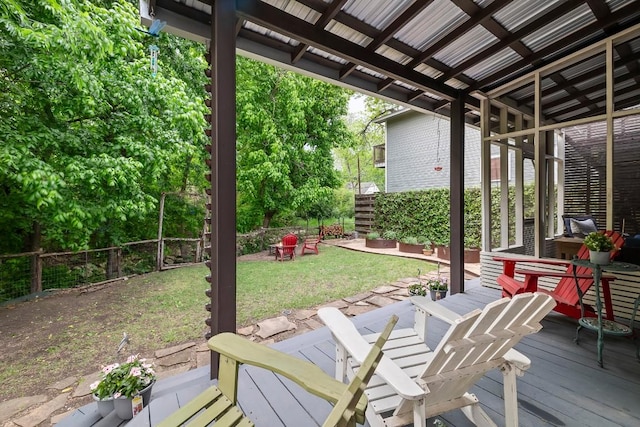 wooden terrace featuring an outdoor fire pit, a fenced backyard, and a lawn