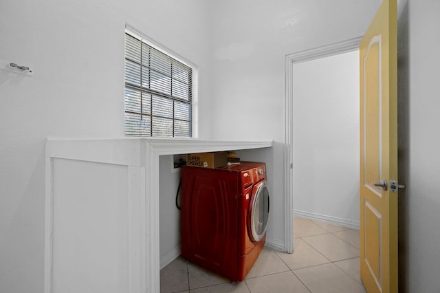 clothes washing area with washer / dryer, laundry area, light tile patterned flooring, and baseboards