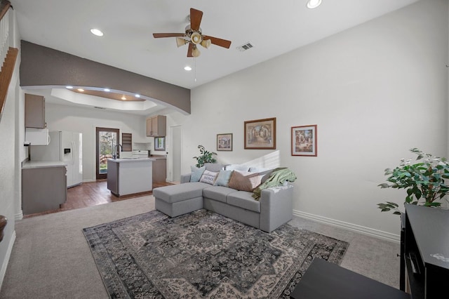 living area featuring arched walkways, a tray ceiling, visible vents, and recessed lighting