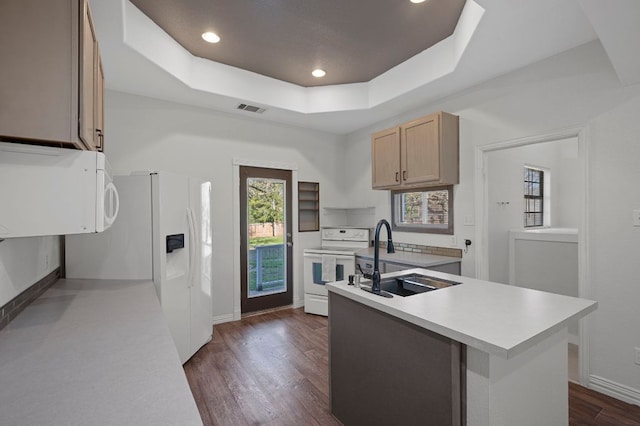 kitchen featuring white appliances, visible vents, a raised ceiling, light countertops, and a sink