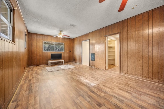 1876 Rocky Rd, Blanco, TX 78606 - unfurnished living room featuring a ceiling fan, wood finished floors, a textured ceiling, and wooden walls