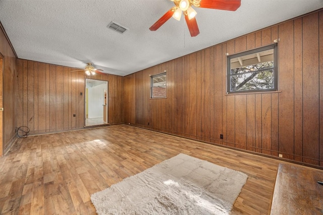 1876 Rocky Rd, Blanco, TX 78606 - empty room with a ceiling fan, hardwood / wood-style flooring, wooden walls, and a textured ceiling