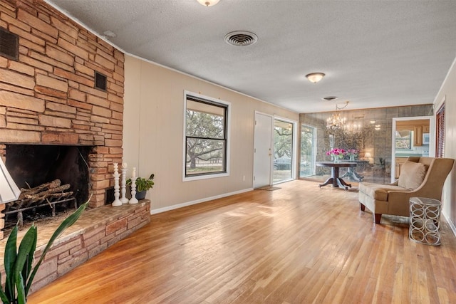 1876 Rocky Rd, Blanco, TX 78606 - sitting room with a textured ceiling, wood finished floors, a chandelier, and a fireplace