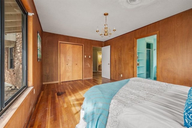 1876 Rocky Rd, Blanco, TX 78606 - bedroom with a chandelier, wooden walls, wood finished floors, and a closet