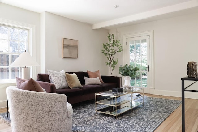 living area with beamed ceiling, wood finished floors, and baseboards