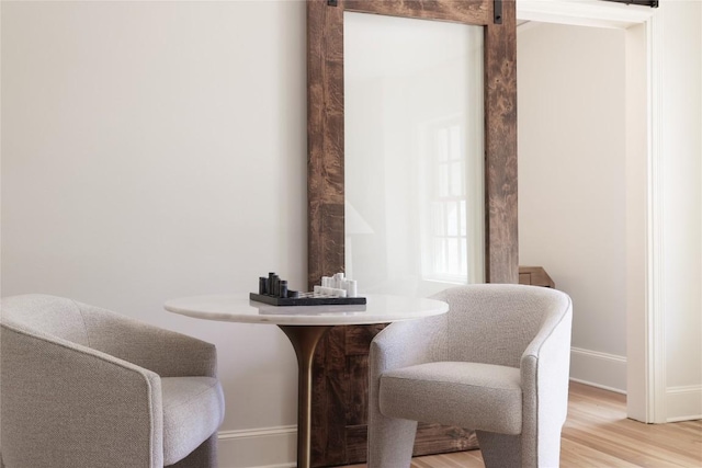 interior space featuring light wood finished floors, a barn door, and baseboards