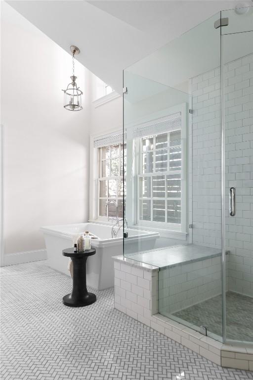 bathroom with a freestanding bath, a stall shower, tile patterned flooring, and a chandelier