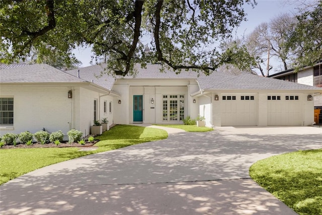 view of front facade with a garage, brick siding, concrete driveway, french doors, and a front yard