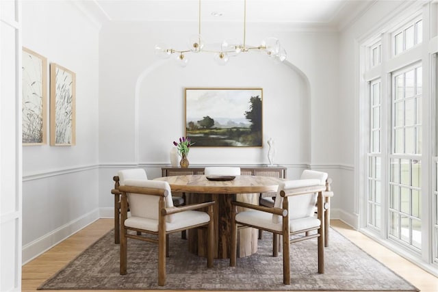 dining area featuring arched walkways, a notable chandelier, crown molding, and wood finished floors