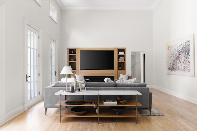 living area with ornamental molding, a high ceiling, and wood finished floors