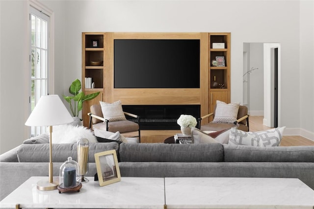 living area featuring built in shelves, wood finished floors, and baseboards