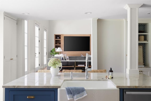 kitchen with light stone counters, open floor plan, a sink, blue cabinets, and dishwashing machine