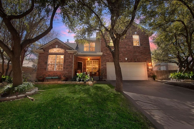 traditional-style home featuring a garage, concrete driveway, brick siding, and a yard