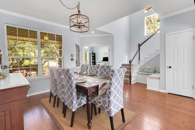 dining room with an inviting chandelier, dark wood-type flooring, ornamental molding, baseboards, and stairs