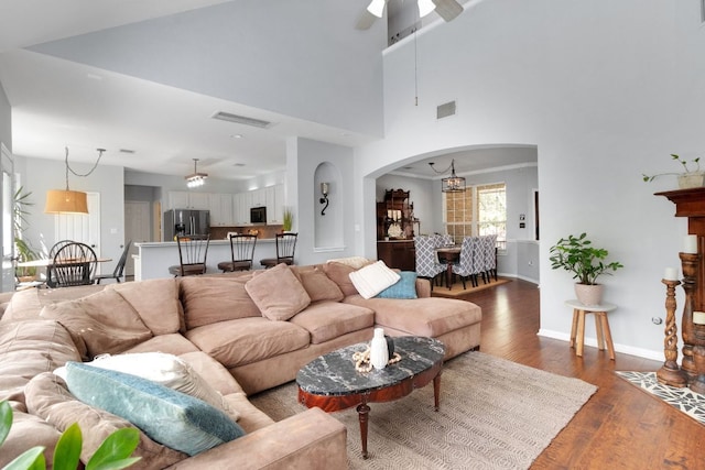 living area with dark wood-style floors, visible vents, arched walkways, and baseboards