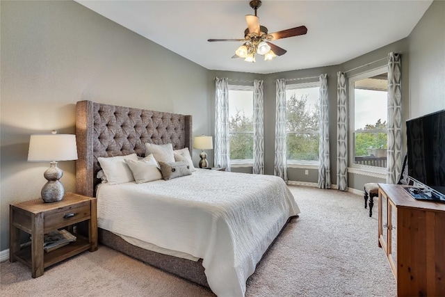 bedroom featuring light carpet, a ceiling fan, and baseboards