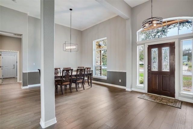 entryway with ornamental molding, baseboards, an inviting chandelier, and wood finished floors