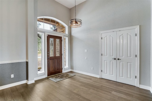 foyer entrance featuring wood finished floors, a towering ceiling, and baseboards