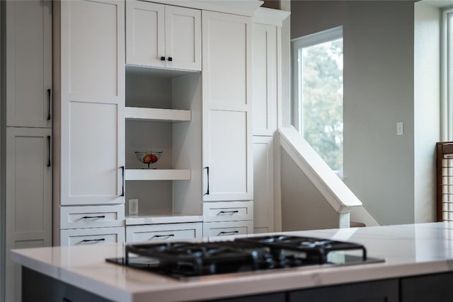 kitchen with black gas cooktop, open shelves, light countertops, and white cabinetry